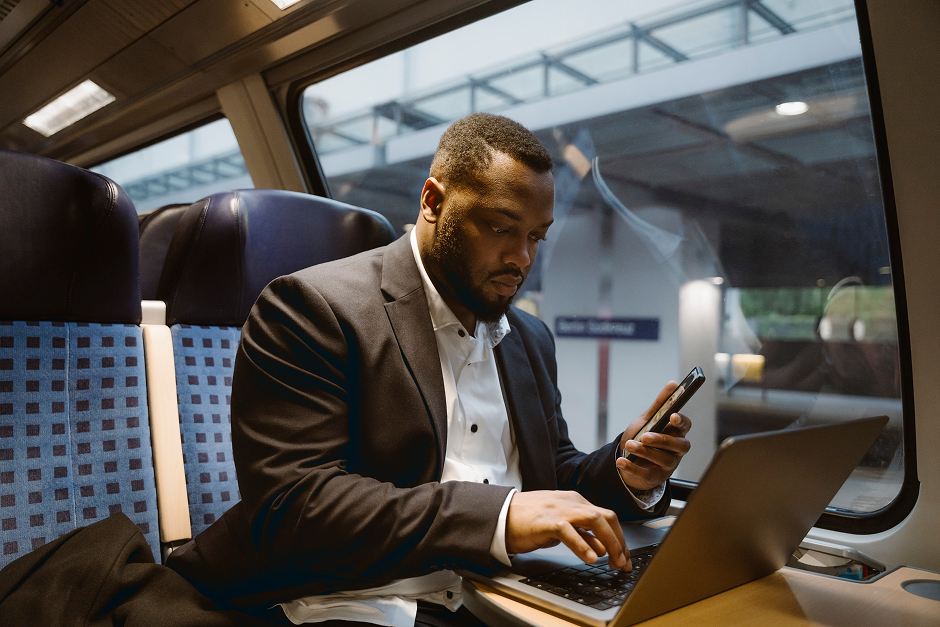 Portrayal of a Capella University online IT student studying on his laptop on a train.