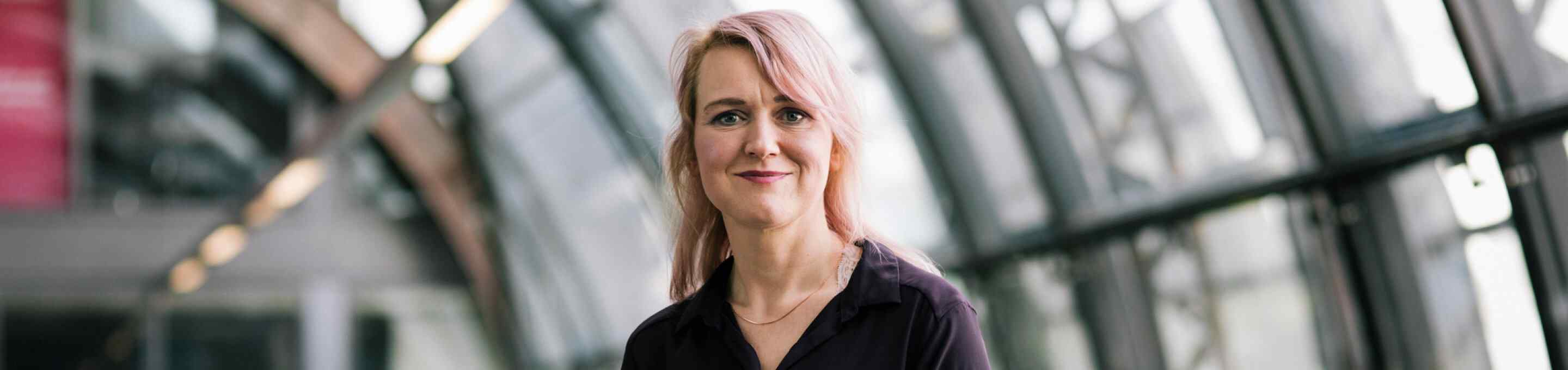 pink haired woman sitting on a desk