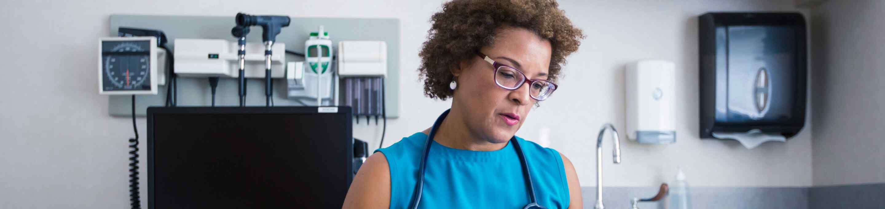 woman doctor in blue blouse looking down in a doctor's office